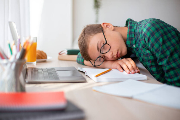 Uitgeput schooljongen slapen tijdens het studeren thuis - Foto, afbeelding