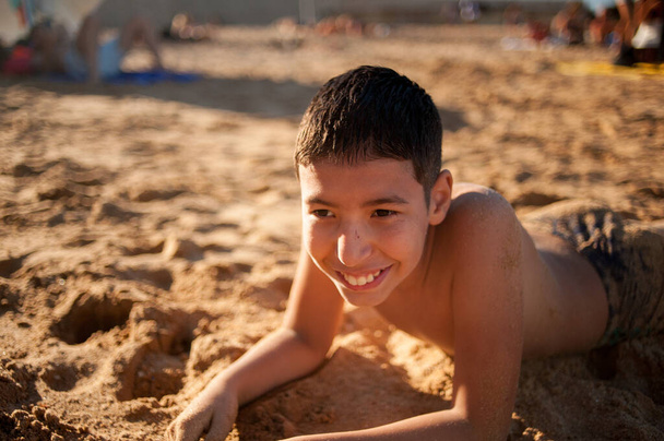 Edessä näkymä latino poika hymyilee leikkii hiekalla rannalla. Kopioi tilaa - Valokuva, kuva