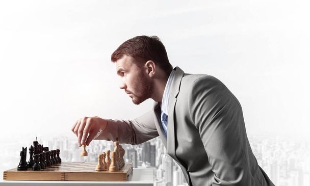 Concentrated businessman playing chess game - Foto, afbeelding
