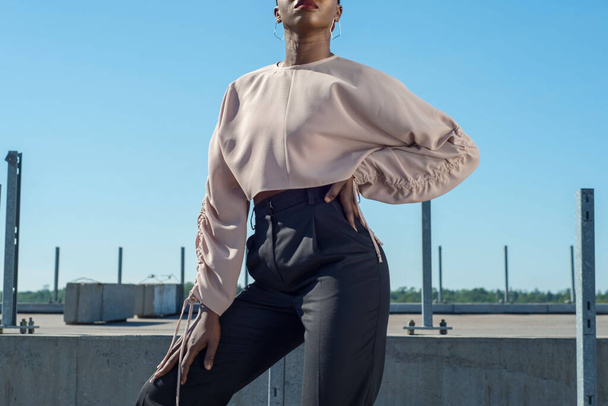 Closeup portrait fashionable dark skinned girl, African girl in a blouse and business pants, posing. Against the background of blue sky. Fashionable black girl, blacks fashion. young Nigerian girl, young African girl, twenty five years old, posing in - Photo, Image
