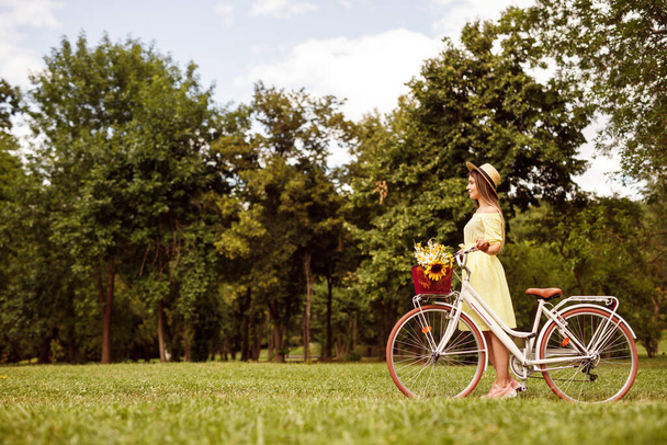 Young woman with bicycle in meadow - Fotó, kép