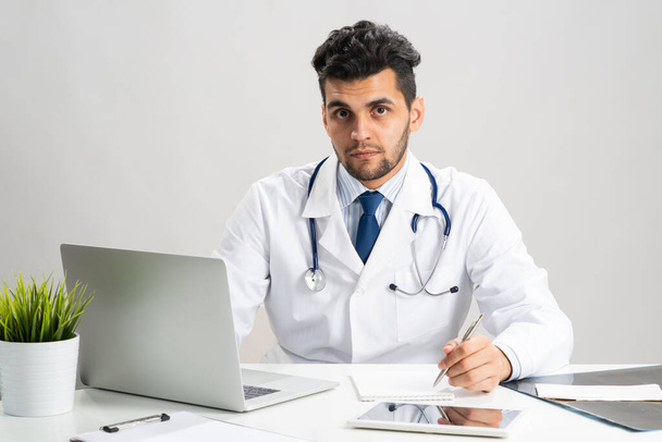 Handsome doctor sitting at desk in office - Foto, immagini