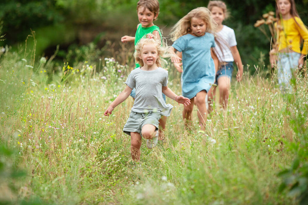 Kids, children running on green meadow, forest. Childhood and summertime - Foto, imagen