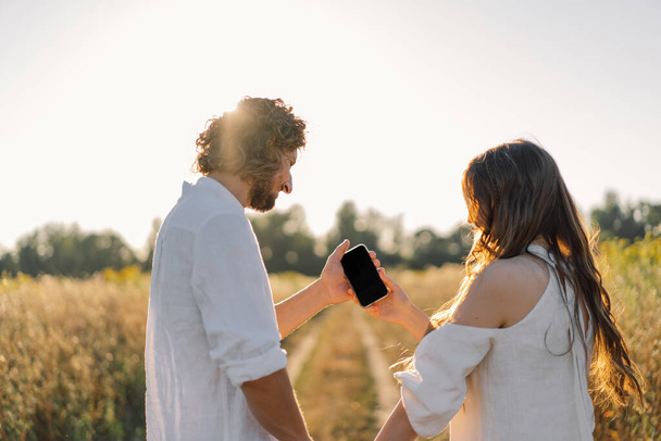 Egy fiatal pár a természetben nézi a telefont. - Fotó, kép