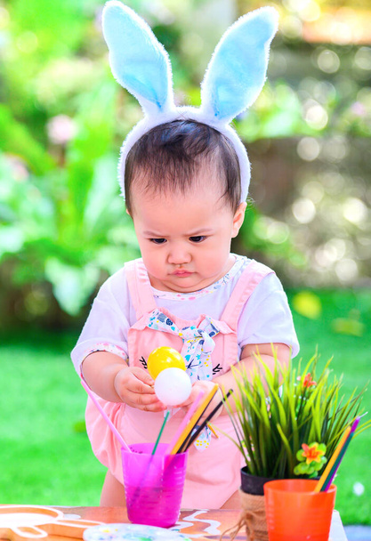 ハッピーイースターの日。カラフルな卵のおもちゃを持つ子供。4月に家族と一緒に家で祝うための幸せと楽しさ. - 写真・画像