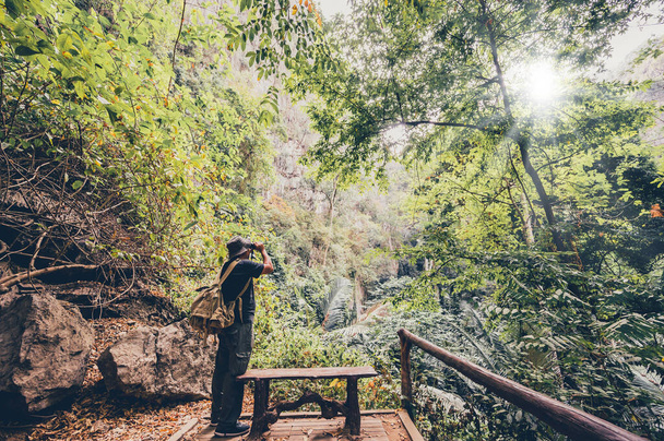 Poszukiwacz przygód trzymający lornetkę do obserwacji ptaków i szlaku turystycznego w lesie i jaskini. Aktywność na świeżym powietrzu i rekreacja na wakacjach letnich. - Zdjęcie, obraz