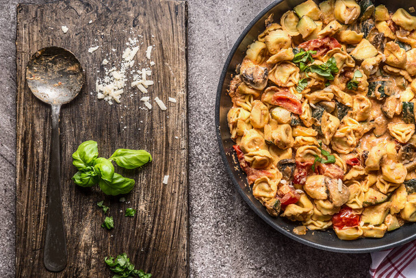 Tortellini étel zöldségmártással és kanállal, felülnézetből. Egészséges vegetáriánus főzés és étkezés. Olasz élelmiszer-koncepció - Fotó, kép
