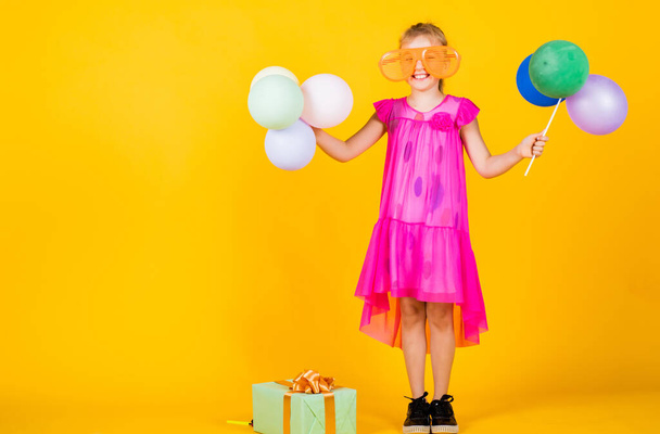 nice holiday party. kid having fun. international childrens day. happy childhood. little child with balloons. Entertainment birthday concept. child having party with balloons and gift box - Fotó, kép