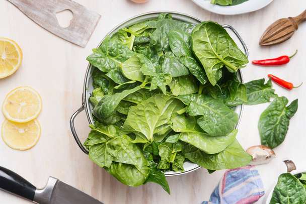 Fresh organic spinach leaves in colander on kitchen table background, top view, close up - Foto, immagini