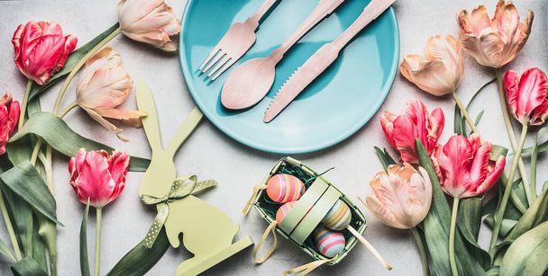 Easter composing with spring tulips , bunny decor, eggs and festive table setting with plate and cutlery, top view, banner - Photo, Image