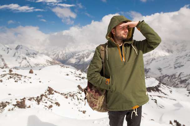 young hipster man hiking in mountains, winter vacation traveling, north, snow, warm clothes, backpack, anorak, jeans, boots - Φωτογραφία, εικόνα