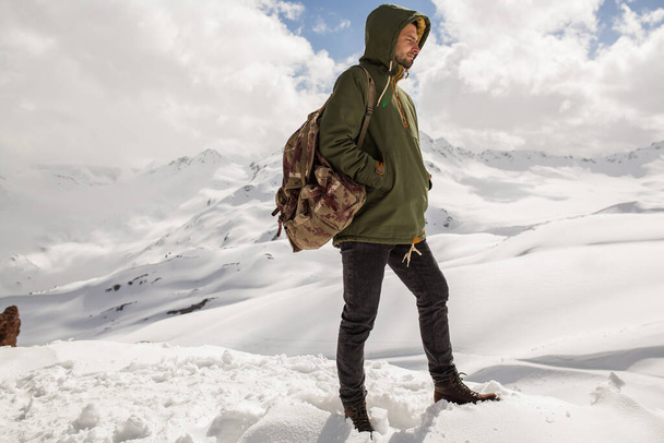 young hipster man hiking in mountains, winter vacation traveling, north, snow, warm clothes, backpack, anorak - Φωτογραφία, εικόνα