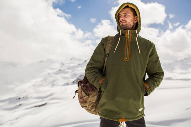 young hipster man hiking in mountains, winter vacation traveling, north, snow, warm clothes, backpack, anorak - Foto, afbeelding