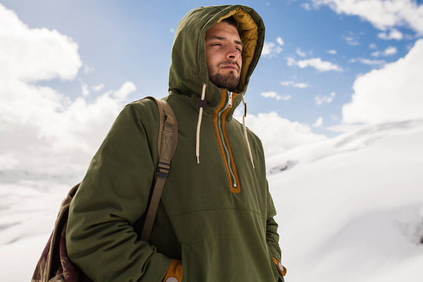 young hipster man hiking in mountains, winter vacation traveling, north, snow, warm clothes, backpack, anorak - 写真・画像