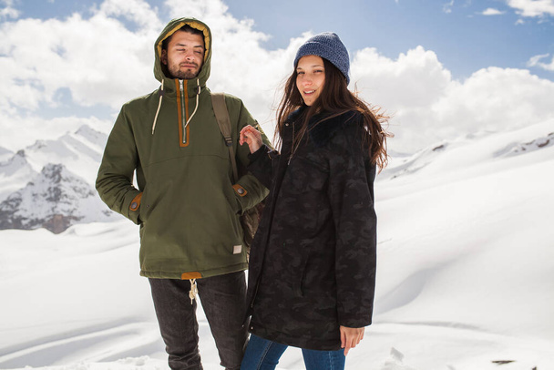 young beautiful hipster couple hiking in mountains, winter vacation traveling, man woman in love, romance, north, snow, warm clothes, jacket, anorak, jeans, hat - Fotografie, Obrázek