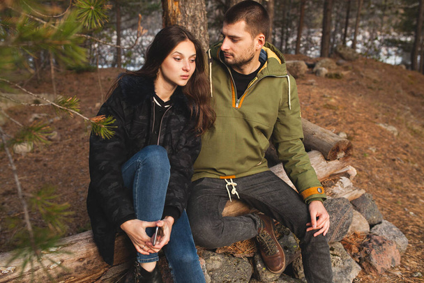 young beautiful hipster man and woman in love traveling together in wild nature, hiking in forest, autumn style apparel, coat, romance, vacation, warm clothes - Foto, afbeelding