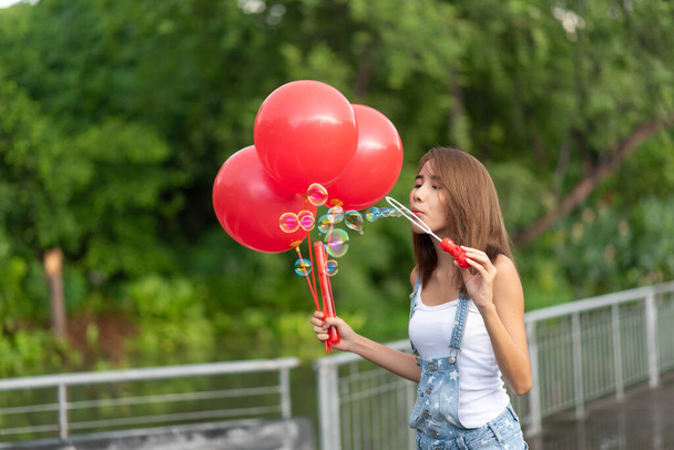 Happy young Asia woman holding red balloons - Foto, afbeelding