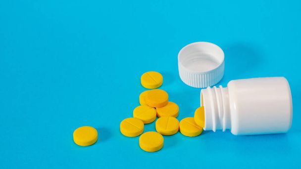 Yellow pills and plastic white bottle - Valokuva, kuva
