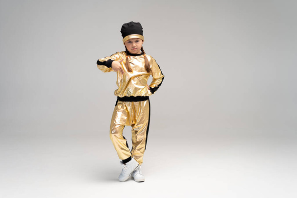Happy little girl in gold suit dancing isolated on white background. - 写真・画像