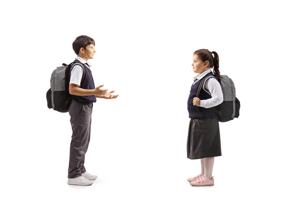 Full length profile shot of pupils in uniforms having a conversation isolated on white background - Foto, Imagem