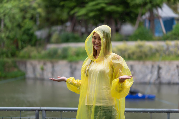Portrait of the women wearing yellow raincoat while raining in rainy season - Photo, Image