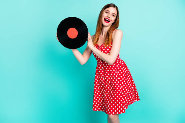Photo of pretty lady good mood hold vinyl vintage turnable sound disk party dj excited laughing wear red dotted retro mini dress isolated vivid teal color background - Foto, Imagen