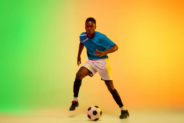 Male soccer, football player training in action isolated on gradient studio background in neon light - Foto, Imagem
