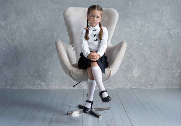 School girl in uniform sit in armchair. - Fotó, kép