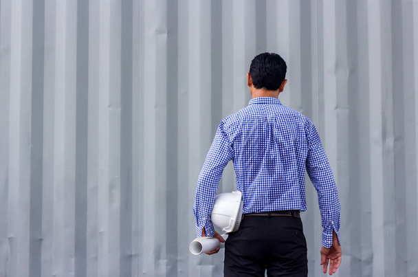 Widok z tyłu portret azjatyckiego inżyniera trzymającego plany pod ścianą stojąc na placu budowy, kopiuj przestrzeń - Zdjęcie, obraz