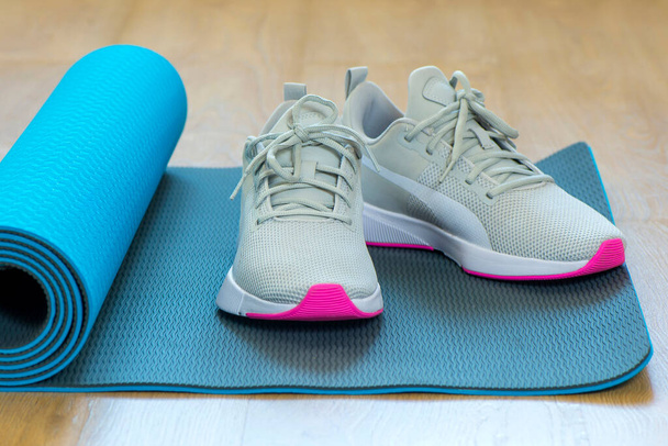 Running shoes grey are on the Mat for gymnastics - Φωτογραφία, εικόνα