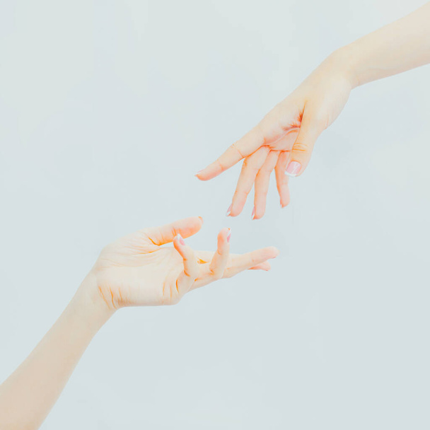 Twee vrouwelijke handen reiken naar elkaar. Gevoeligheid, schoonheid, communicatie. Huidverzorging, massage. Aantrekkingskracht en aanraking. Handen dicht. - Foto, afbeelding