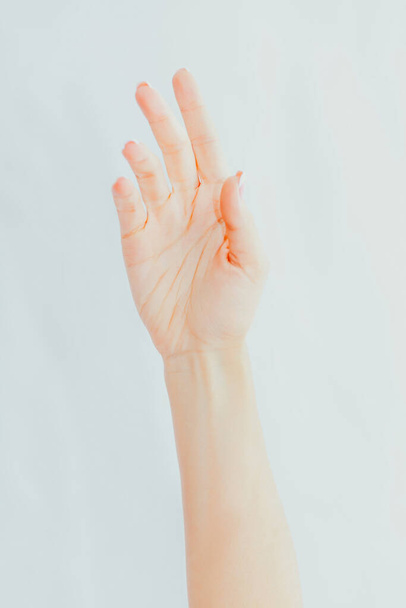 Female hand with french manicure on gray background. Palm view - Valokuva, kuva