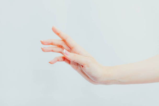 Female hand with french manicure on gray background. Side view - Valokuva, kuva
