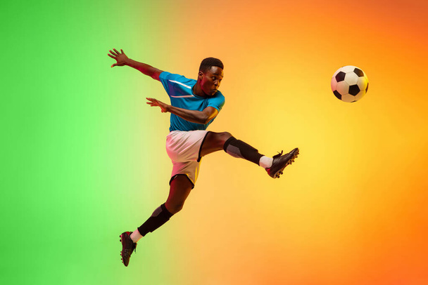 Male soccer, football player training in action isolated on gradient studio background in neon light - Foto, immagini