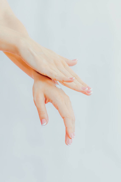 Woman with french manicure applies cream to her hands. Hand skin care and massage. Hands close up - Fotoğraf, Görsel