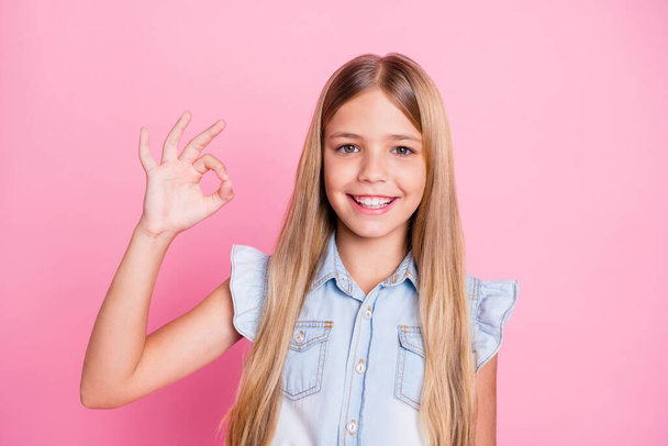 Portrait of positive cheerful kid girl recommend great ads show okay symbol wear stylish clothes isolated over pastel color background - Photo, Image