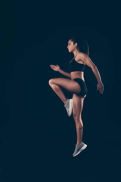 Vertical full size profile photo short sport suit lady practicing warm up before sprint run jogging isolated black background - Fotoğraf, Görsel