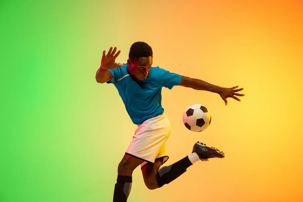 Male soccer, football player training in action isolated on gradient studio background in neon light - Fotoğraf, Görsel