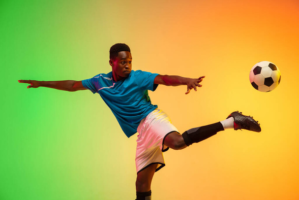 Male soccer, football player training in action isolated on gradient studio background in neon light - Foto, Imagem