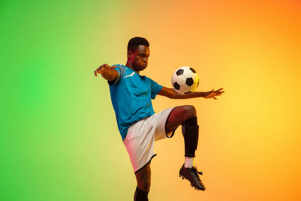 Male soccer, football player training in action isolated on gradient studio background in neon light - Fotó, kép