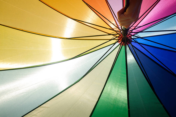 Colorful umbrella protects from the sun a summer day, blue sky background. - Photo, Image