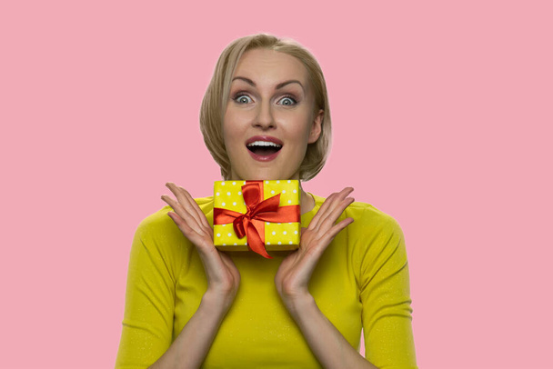 Happy expressive woman with gift box looking at camera. - Photo, Image