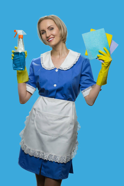 Gai femme de ménage en uniforme tenant chiffons et détergent. - Photo, image