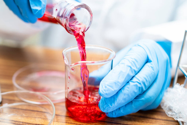 Фляжка Эрленмейера, коническая стеклянная фляжка с раствором жидкости красного цвета в лаборатории химии на белом фоне. - Фото, изображение