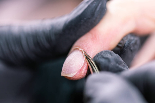 Manikiurzystka używa elektrycznego wiertarki do paznokci w salonie piękności. idealny paznokcie manicure proces zbliżenie z wybuch latające gruzy. - Zdjęcie, obraz