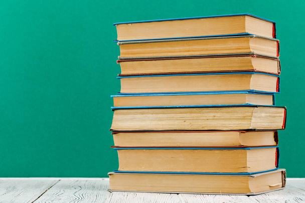 A stack of books on a white table on a green background - Photo, Image