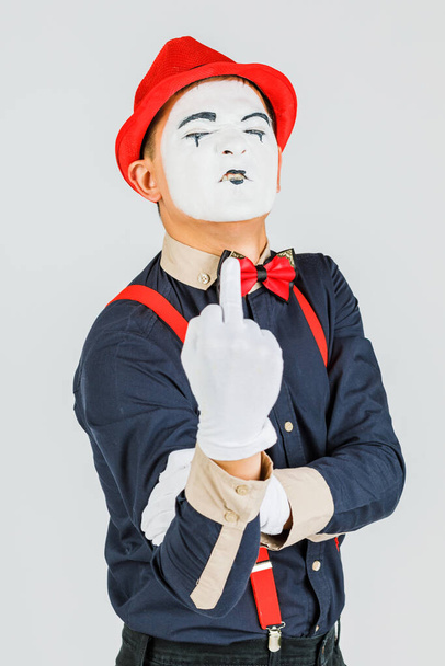 Clown met rode bretels en rode hoed op witte achtergrond. - Foto, afbeelding