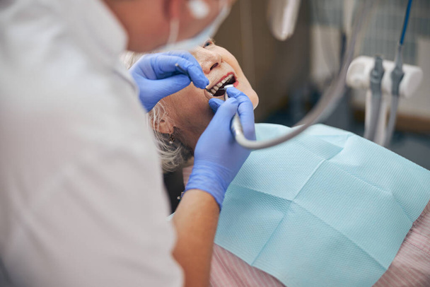 Mężczyzna dentysta pracujący z wiertłem dentystycznym u pacjenta - Zdjęcie, obraz