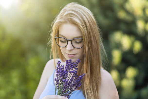 Cute young woman is posing with glasses holding a bouquet of lavender. - Foto, Imagem