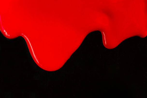 Red paint flows on a black background. Copy space. - Photo, Image